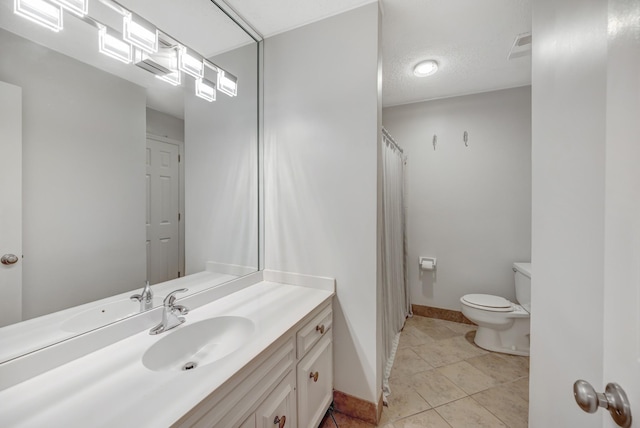 bathroom featuring tile patterned flooring, a textured ceiling, vanity, and toilet