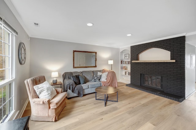 living room with ornamental molding, a fireplace, and light hardwood / wood-style flooring