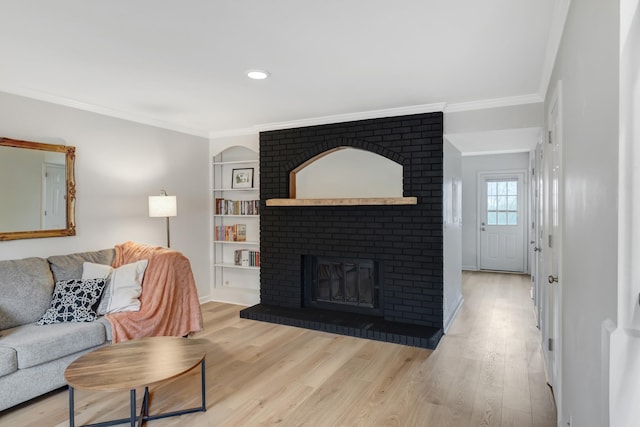 living room with light hardwood / wood-style floors, a brick fireplace, and crown molding