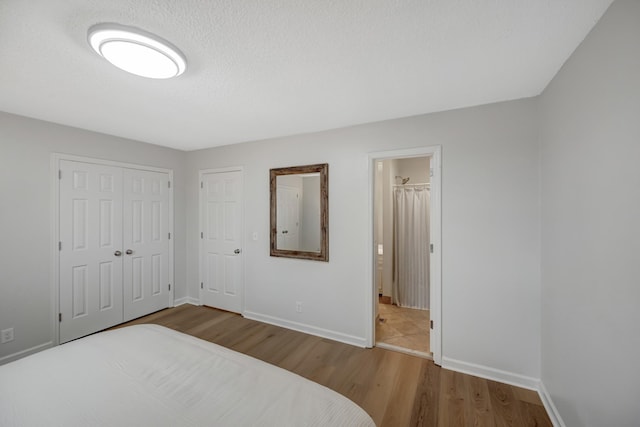 bedroom featuring ensuite bathroom, wood-type flooring, and a textured ceiling