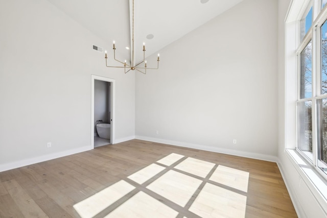 unfurnished dining area with light wood finished floors, baseboards, visible vents, and a chandelier