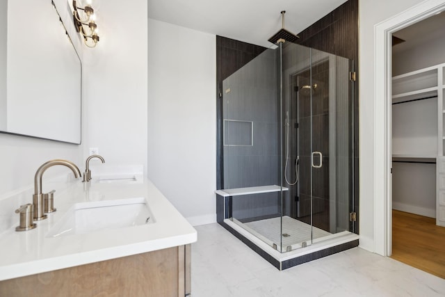 full bathroom featuring baseboards, a spacious closet, a sink, and a shower stall