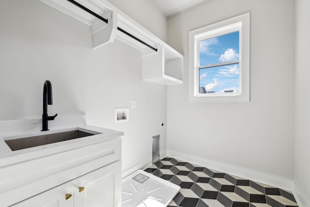 laundry room featuring washer hookup, a sink, baseboards, cabinet space, and tile patterned floors