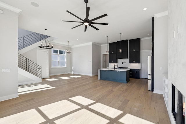 kitchen with light countertops, ornamental molding, freestanding refrigerator, and light wood-style floors