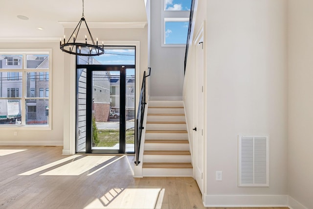 entryway with a healthy amount of sunlight, stairs, visible vents, and wood finished floors