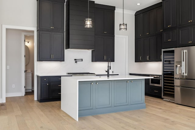 kitchen featuring stainless steel appliances, light countertops, a sink, and light wood finished floors