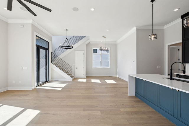 kitchen featuring light wood-type flooring, blue cabinetry, ornamental molding, and decorative light fixtures