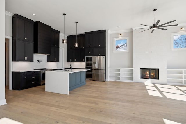 kitchen with high quality appliances, light countertops, dark cabinetry, light wood-style floors, and a fireplace