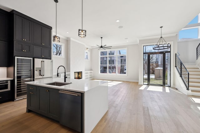 kitchen with appliances with stainless steel finishes, light countertops, a sink, and open floor plan