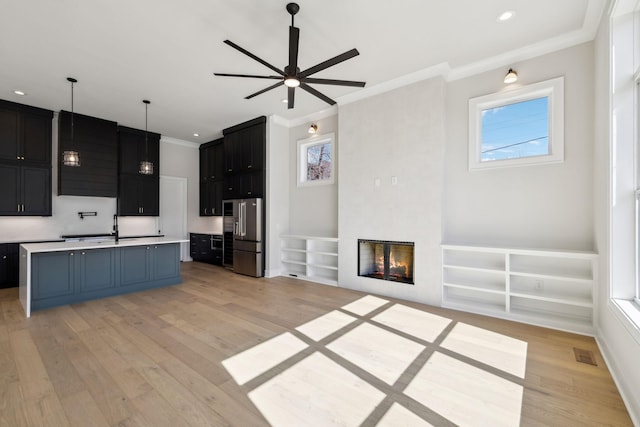 kitchen featuring light wood finished floors, visible vents, light countertops, a tiled fireplace, and high quality fridge