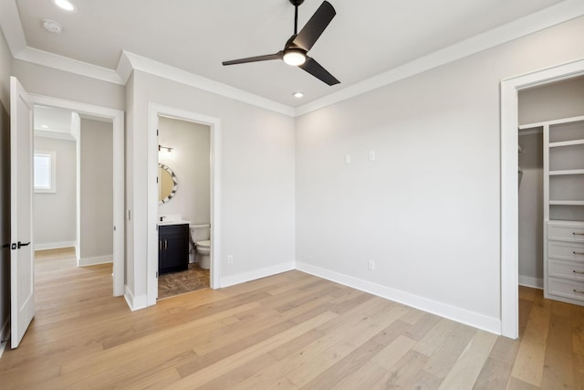 unfurnished bedroom featuring ornamental molding, light wood-type flooring, a spacious closet, and baseboards