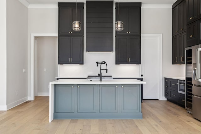 kitchen with a sink, light countertops, crown molding, and an island with sink