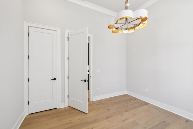 unfurnished room featuring light wood-type flooring, a notable chandelier, and baseboards