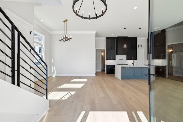 kitchen with light wood-style flooring, a chandelier, light countertops, and ornamental molding