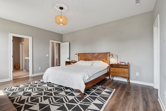 bedroom featuring ensuite bathroom and dark wood-type flooring