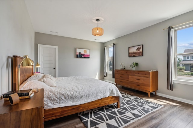 bedroom featuring multiple windows and dark hardwood / wood-style flooring