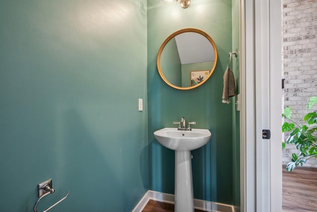 bathroom featuring hardwood / wood-style floors and brick wall