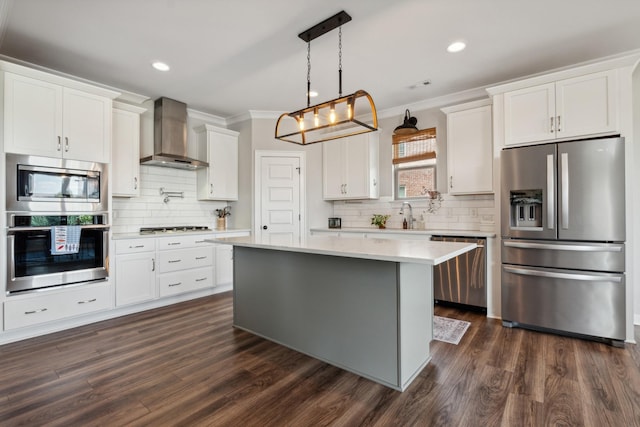 kitchen featuring wall chimney exhaust hood, stainless steel appliances, dark hardwood / wood-style flooring, crown molding, and white cabinets