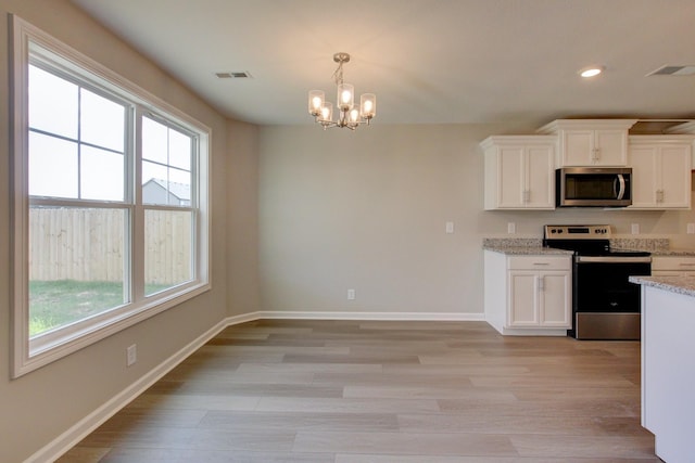 kitchen with appliances with stainless steel finishes, a notable chandelier, light hardwood / wood-style floors, light stone counters, and white cabinetry