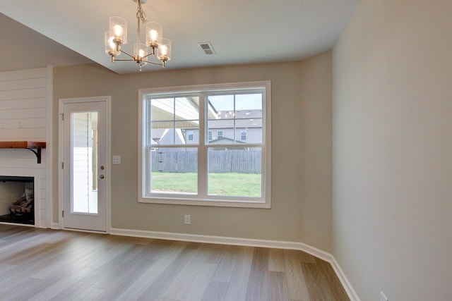 interior space featuring a fireplace, light hardwood / wood-style flooring, a wealth of natural light, and a notable chandelier