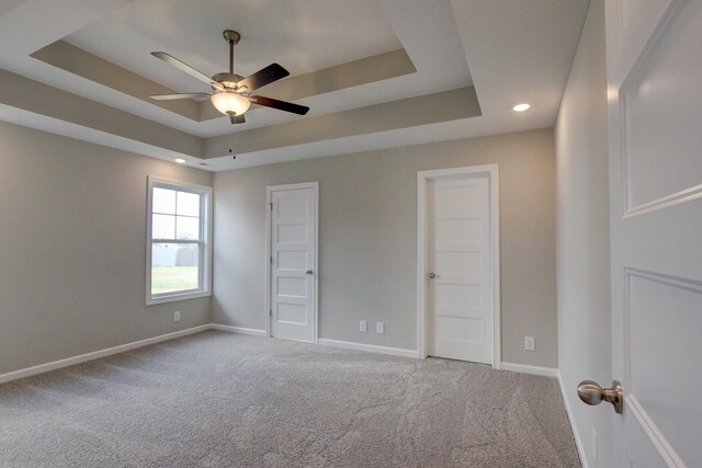 unfurnished room featuring carpet flooring, a tray ceiling, and ceiling fan