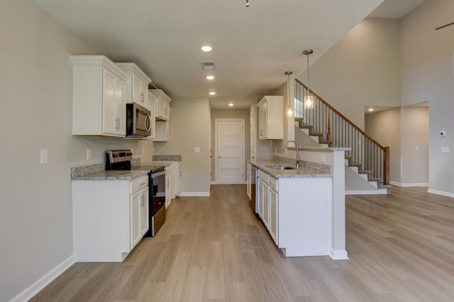 kitchen with white cabinetry, sink, stainless steel appliances, and decorative light fixtures