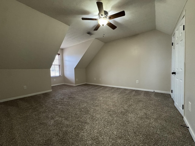 additional living space with a textured ceiling, ceiling fan, dark carpet, and lofted ceiling