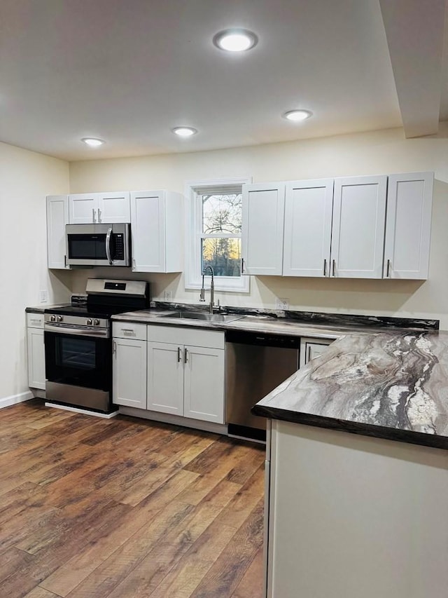 kitchen featuring dark hardwood / wood-style flooring, white cabinetry, sink, and appliances with stainless steel finishes