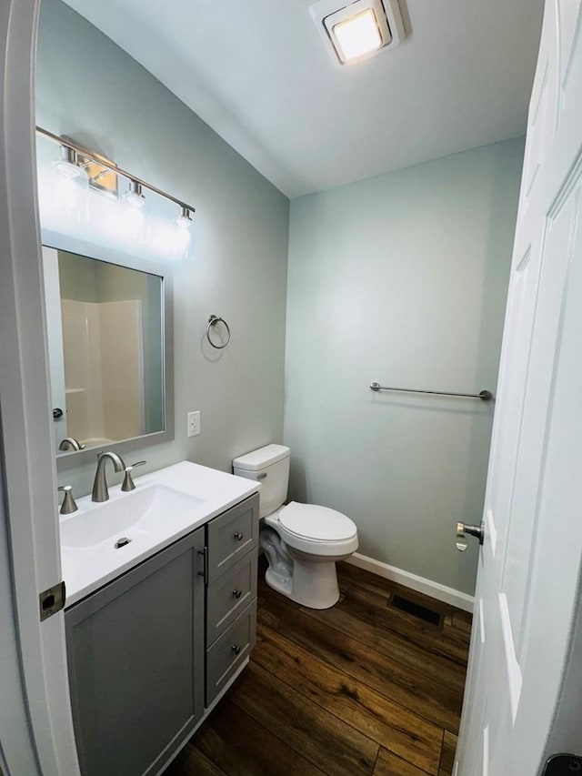 bathroom featuring a shower, vanity, hardwood / wood-style flooring, and toilet