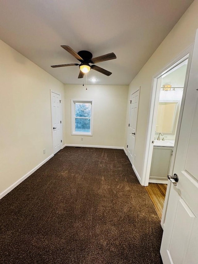 unfurnished room featuring dark colored carpet, ceiling fan, and sink