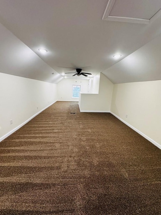 bonus room with ceiling fan, dark carpet, and vaulted ceiling