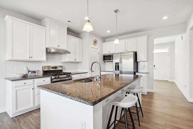 kitchen with a kitchen island with sink, white cabinets, sink, light wood-type flooring, and stainless steel appliances