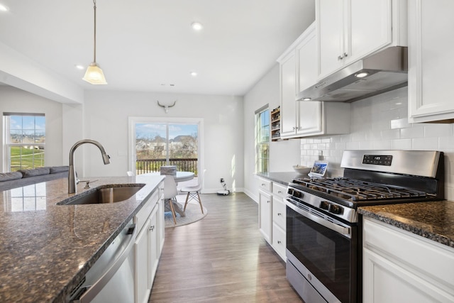 kitchen featuring dark wood-type flooring, white cabinets, sink, hanging light fixtures, and stainless steel appliances