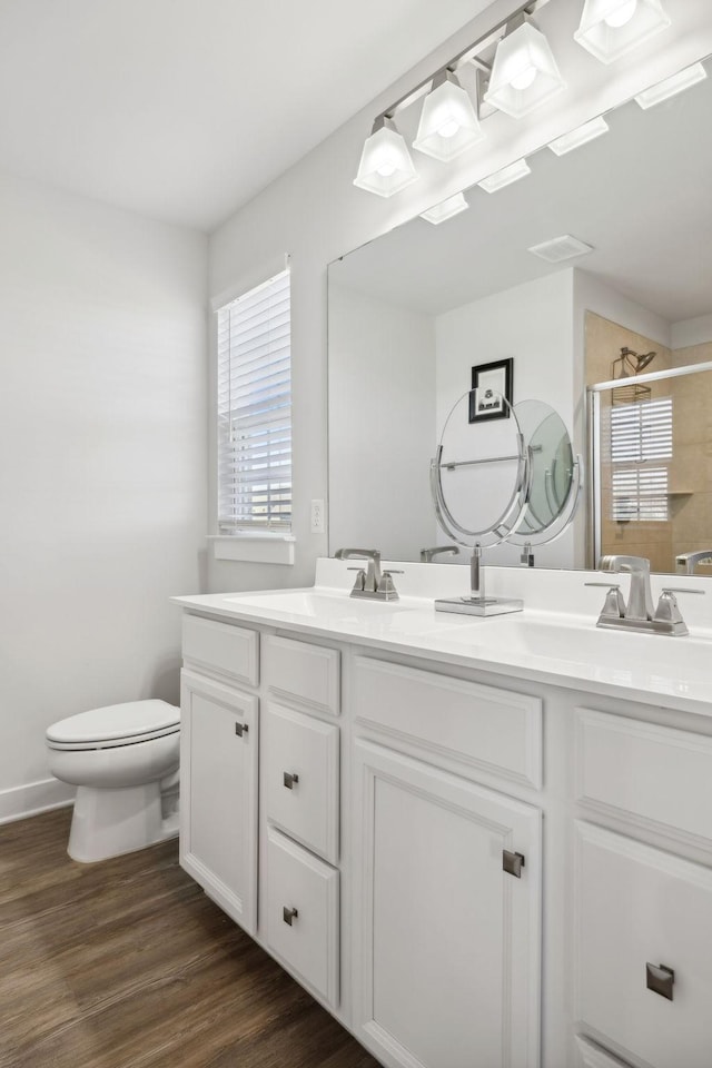 bathroom with a shower with door, vanity, wood-type flooring, and toilet