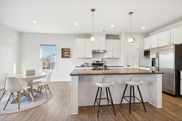 kitchen featuring appliances with stainless steel finishes, sink, white cabinets, light hardwood / wood-style floors, and an island with sink