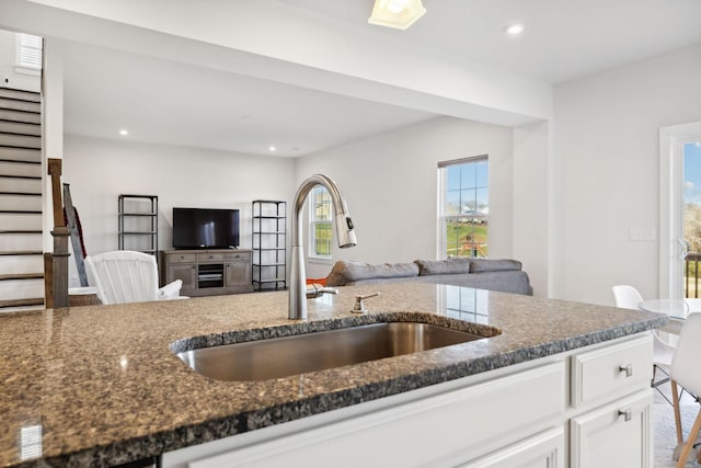 kitchen featuring white cabinetry, dark stone counters, and sink