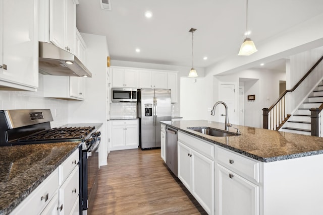 kitchen with sink, stainless steel appliances, dark hardwood / wood-style flooring, pendant lighting, and a center island with sink