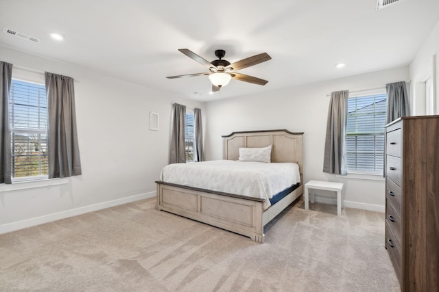 bedroom with multiple windows, ceiling fan, and light carpet