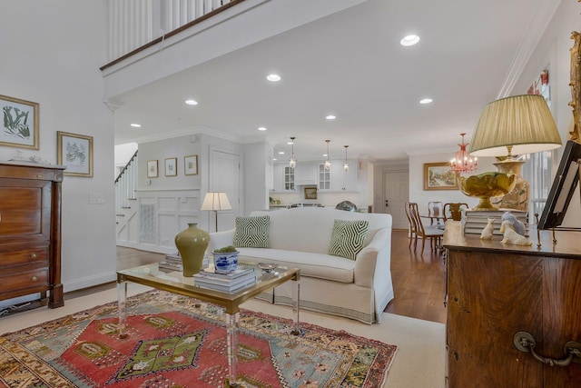 living room with light wood-type flooring, crown molding, and a notable chandelier