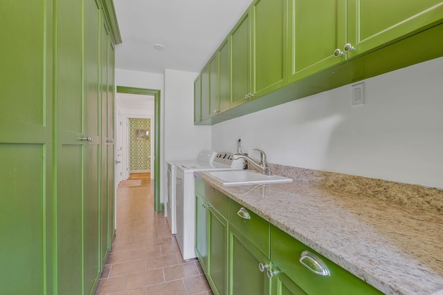 clothes washing area featuring cabinets, sink, light tile patterned floors, and washer and dryer