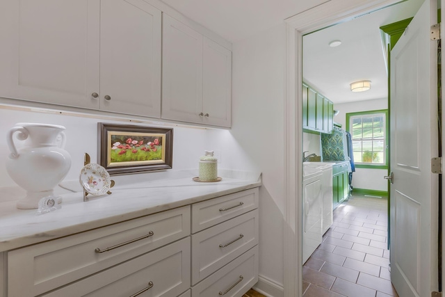 kitchen with white cabinets, washing machine and dryer, and light stone countertops