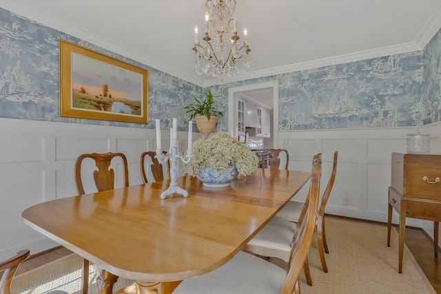 dining space with light hardwood / wood-style floors, ornamental molding, and an inviting chandelier