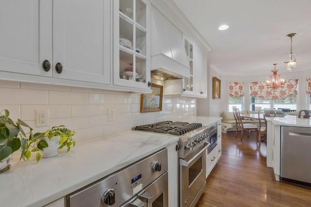 kitchen with white cabinetry, stainless steel appliances, dark hardwood / wood-style flooring, a notable chandelier, and pendant lighting