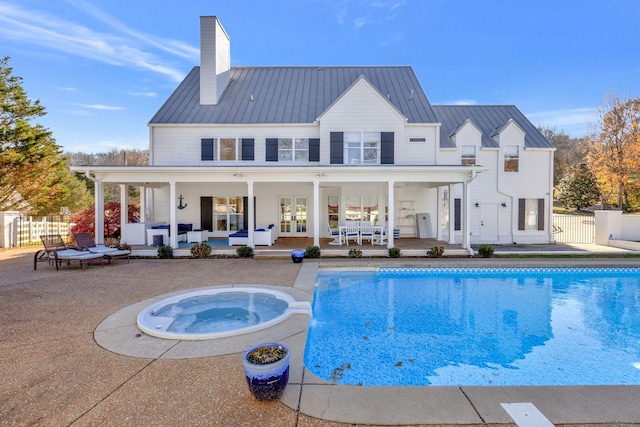 rear view of property featuring an outdoor living space, a swimming pool with hot tub, a patio, and french doors