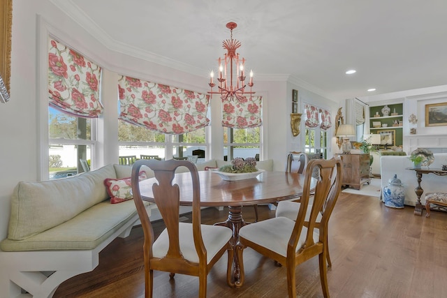 dining area featuring hardwood / wood-style flooring, built in shelves, ornamental molding, and a chandelier