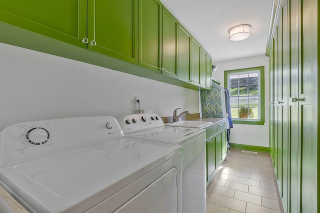 laundry room featuring cabinets, light tile patterned floors, washing machine and dryer, and sink