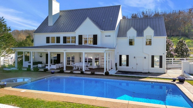 210 Green Rd, Franklin, TN 37069 - back of property with a patio area, a chimney, an outdoor hangout area, a metal roof, and a pool with connected hot tub