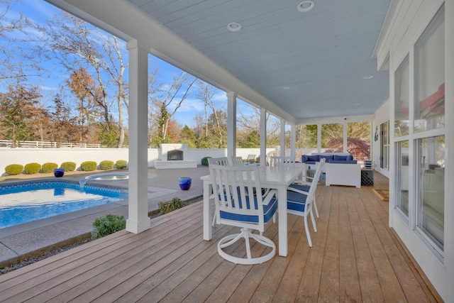 deck featuring an outdoor living space with a fireplace and a fenced in pool