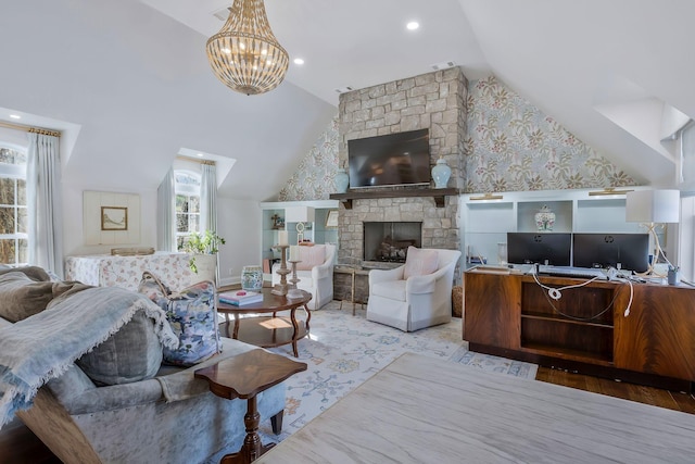 living room featuring light hardwood / wood-style flooring, a notable chandelier, lofted ceiling, and a stone fireplace