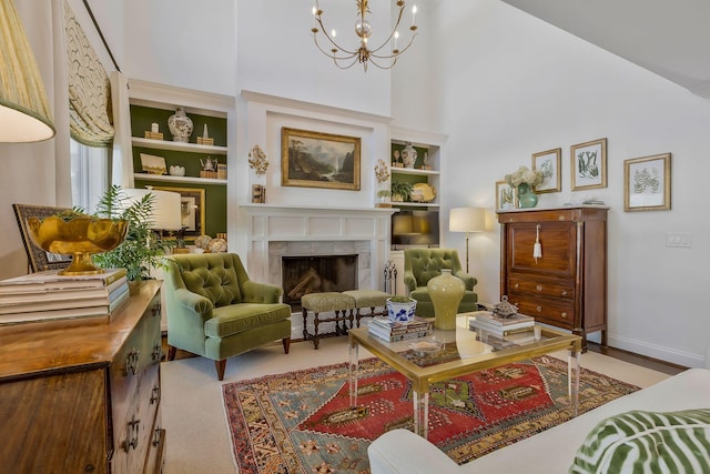 living area featuring a tiled fireplace, built in features, a high ceiling, and a notable chandelier